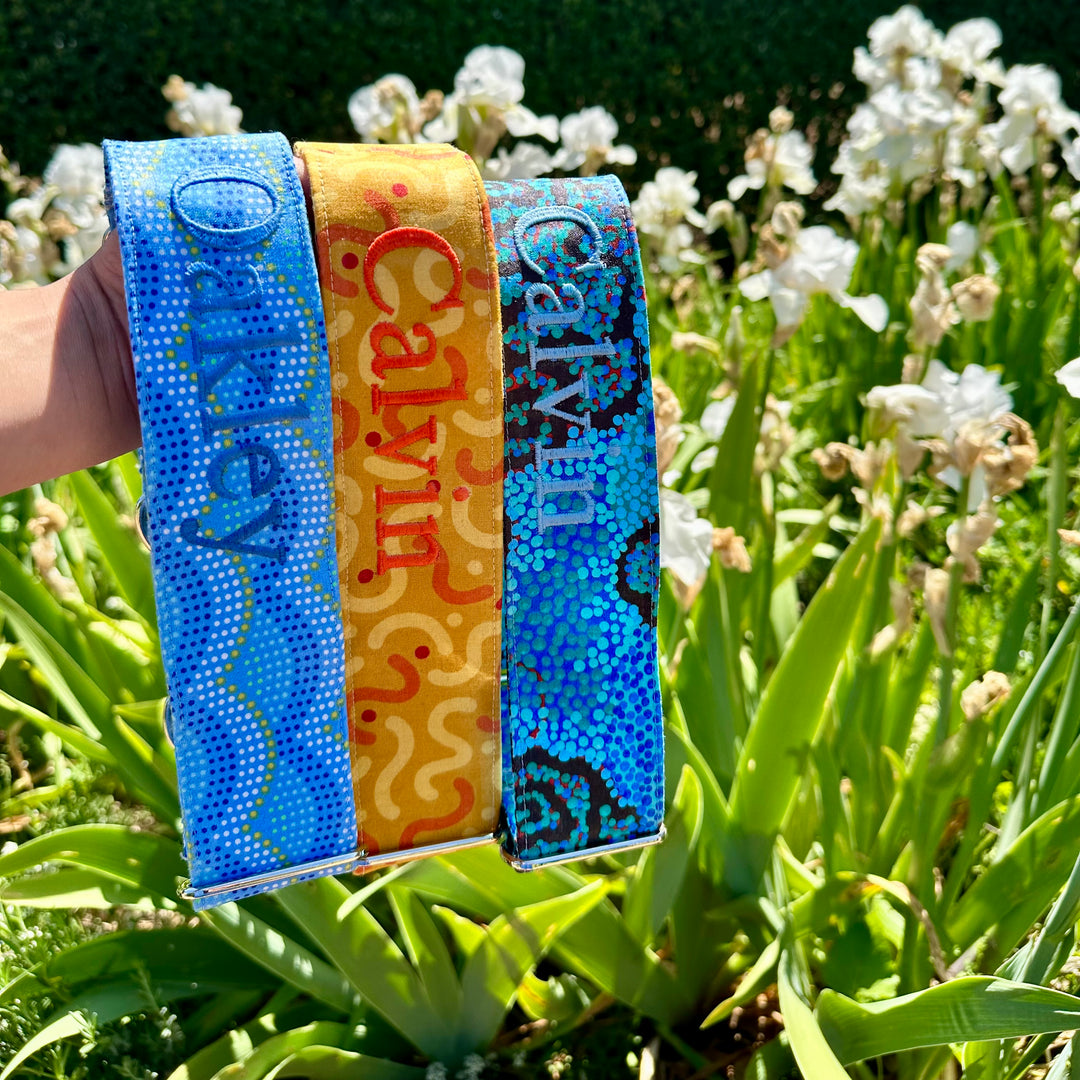Summer bright martingale dog collars with personalisation, custom made, holding in front of flowers