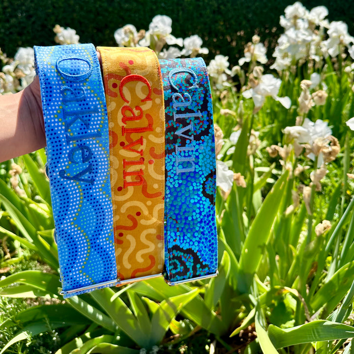 Summer bright martingale dog collars with personalisation, custom made, holding in front of flowers